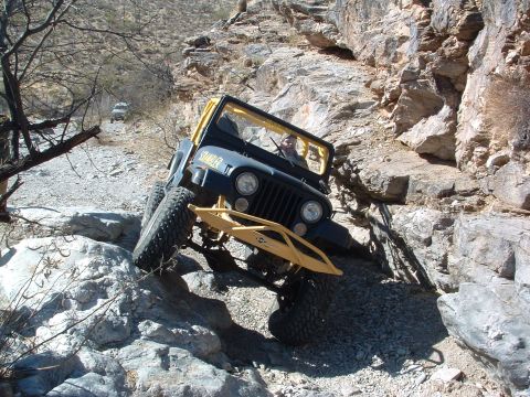 1981 Ford F-150 - A modified Jeep CJ-7 navigates a rocky off-road trail, with another vehicle in the background.