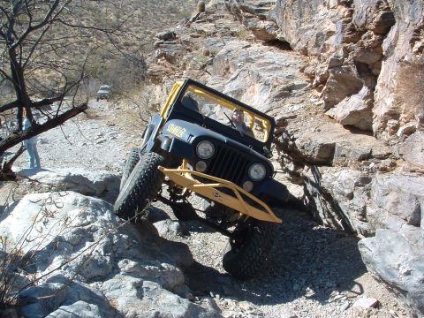 1981 Ford F-150 - A modified Jeep CJ-7 navigates a challenging rocky terrain, demonstrating its off-road capabilities.