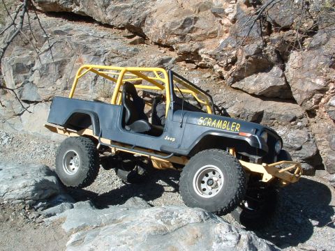 1981 Ford F-150 - A blue Jeep CJ-8 Scrambler navigates a challenging rocky trail, its off-road capabilities.