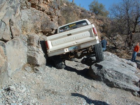 1981 Ford F-150 - A white Ford pickup truck navigates a rocky, off-road trail with two people watching.