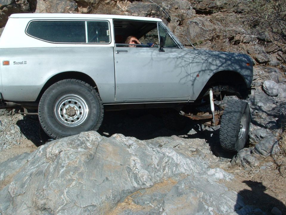 Silver International Scout II off-roading on rocks. Driver visible