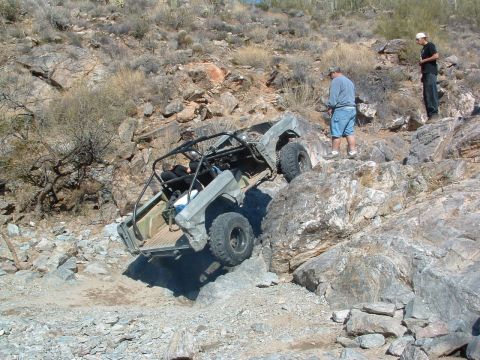 1981 Ford F-150 - An off-road vehicle attempts to climb a challenging rocky incline while two onlookers observe the action.