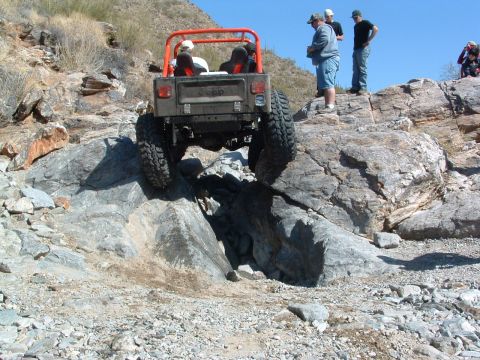 1981 Ford F-150 - A Jeep navigates a difficult rocky terrain, with onlookers observing the challenging off-road maneuver.