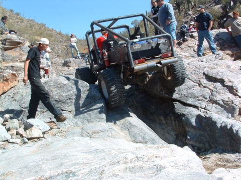 1981 Ford F-150 - A modified off-road buggy tackles a challenging rocky terrain with spectators observing the action.