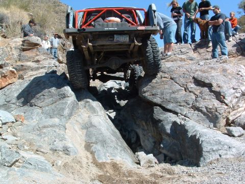1981 Ford F-150 - A modified truck navigates a difficult rocky terrain with spectators observing the action.