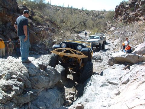 1981 Ford F-150 - Several off-road vehicles traverse a challenging rocky terrain in a desert canyon.