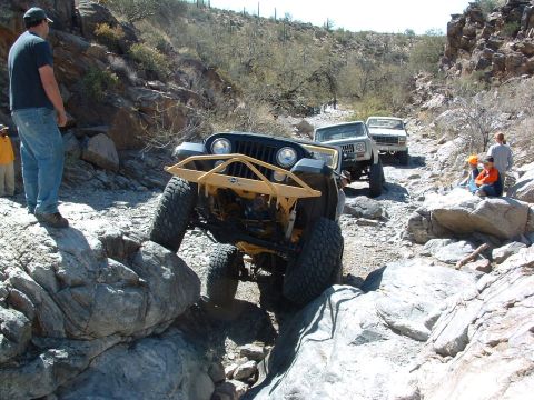 1981 Ford F-150 - Off-road vehicles tackle a challenging rocky trail, with a Jeep Wrangler leading the pack.
