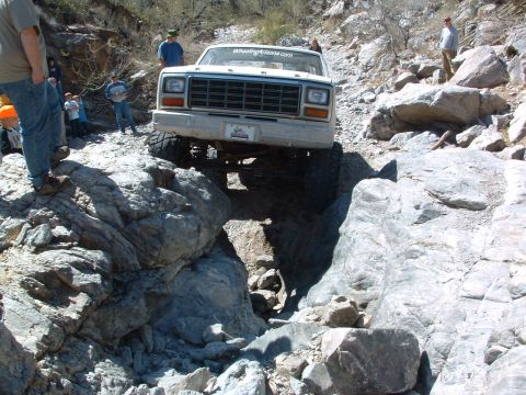1981 Ford F-150 - Ford F-Series truck carefully maneuvers over large rocks on an off-road trail.