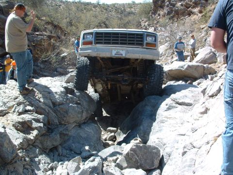 1981 Ford F-150 - This modified truck is carefully maneuvering through a challenging rocky obstacle on an off-road trail.