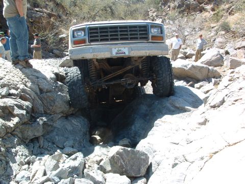1981 Ford F-150 - A white Ford truck with a prominent grille navigates a challenging rocky terrain.