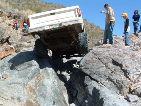 1981 Ford F-150 - A 1981 Ford F-150 tackles a challenging rocky terrain, with onlookers observing the off-road adventure.