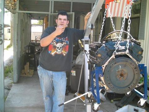 1986 Ford Bronco - A V8 engine is suspended by chains from an engine hoist, ready for installation or removal.