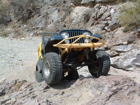 1981 Ford F-150 - Jeep CJ-7 with custom front bumper and large off-road tires on a rocky trail.