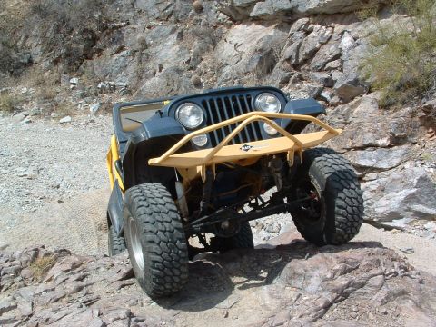1981 Ford F-150 - A yellow Jeep CJ-7 is shown off-road with a custom bumper and large tires.