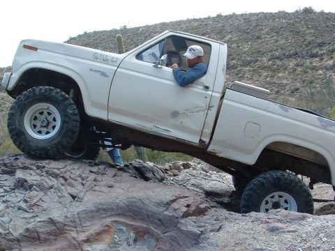 1981 Ford F-150 - This white Ford F-150 navigates a rocky desert terrain, its off-road capabilities.