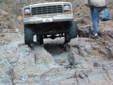 1981 Ford F-150 - A white Ford F-150 navigates a rocky trail, demonstrating its off-road capabilities.