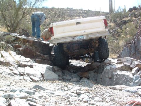 1981 Ford F-150 - Off-road truck carefully maneuvers over large rocks on a desert trail.
