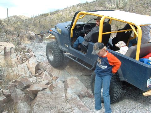 1981 Ford F-150 - Modified Jeep CJ-7 tackling a challenging off-road course in a desert landscape.