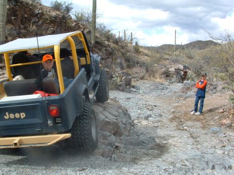1981 Ford F-150 - A Jeep navigates a rocky desert path with two children present.