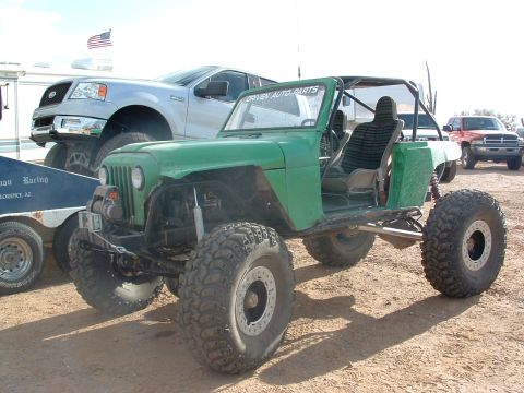 1981 Ford F-150 - This heavily modified off-road jeep features oversized tires and a custom roll cage, seen here alongside a Ford F-150.