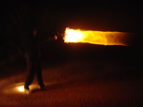 1981 Ford F-150 - A person ignites a flamethrower, creating a bright, fiery stream against the dark night sky.