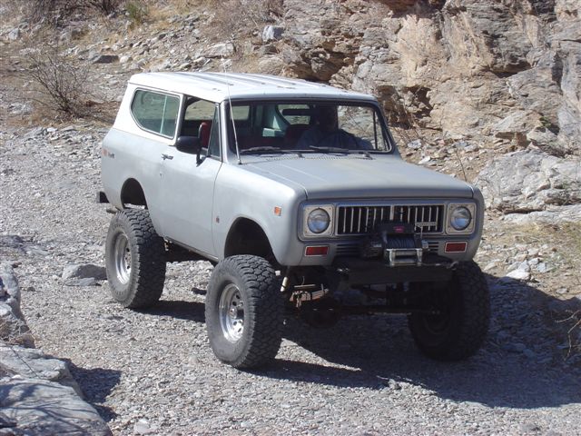 Silver International Harvester Scout II with a winch, lifted suspension, and off-road tires on a rocky trail