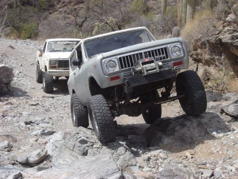 1981 Ford F-150 - Two off-road vehicles navigate a rocky desert trail.