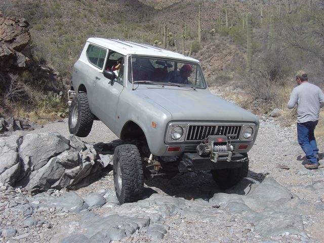 Off-road vehicle navigating rocky terrain. It has a white roof and a winch on the front