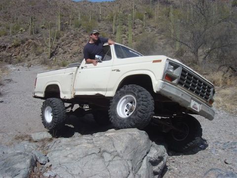 1981 Ford F-150 - Pickup truck with lifted suspension and large tires is driven over rocks in a desert landscape.