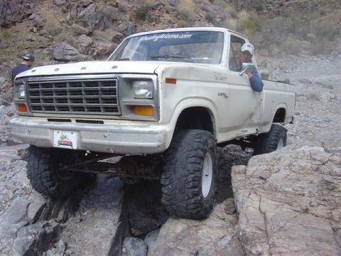 1981 Ford F-150 - This modified Ford pickup truck is shown off-roading on a rocky trail, with its large tires providing clearance for the obstacles.