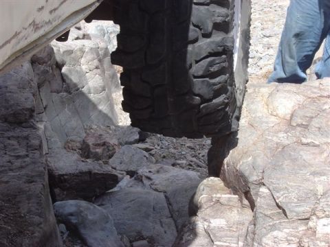 1981 Ford F-150 - A vehicle navigates a narrow, rocky passage, with its tire close to the canyon walls.