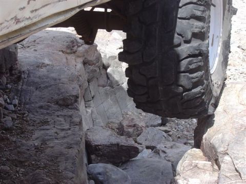 1981 Ford F-150 - A truck navigates a rocky terrain, with its tire precariously balanced.