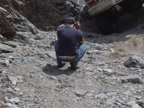 1981 Ford F-150 - A person squats on a rocky path while a vehicle is parked above on the trail.
