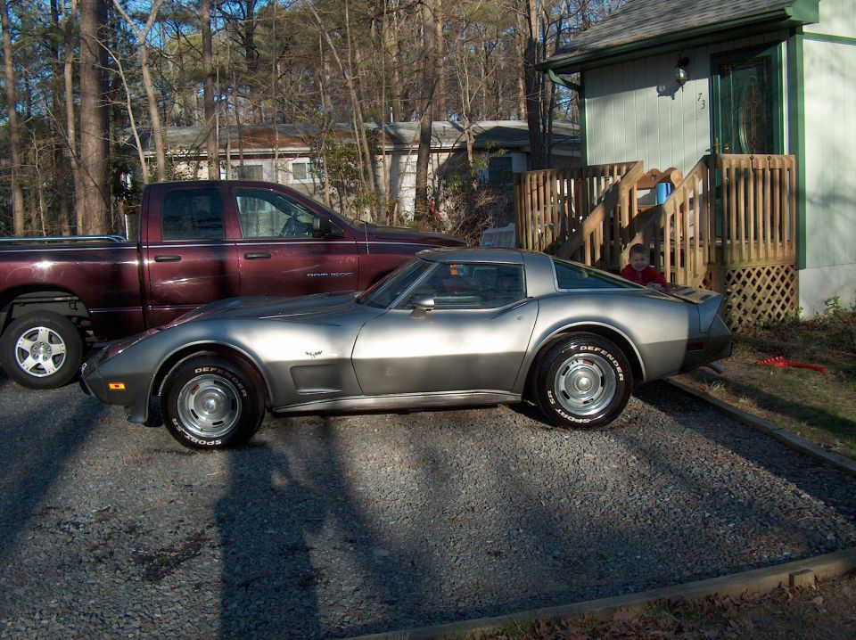 Silver sports car parked next to a maroon pickup truck in a driveway