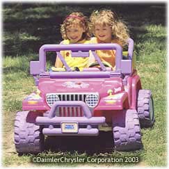 2006 Ford F1 - A pink toy jeep, resembling a Jeep Wrangler, is driven by two young girls outdoors.
