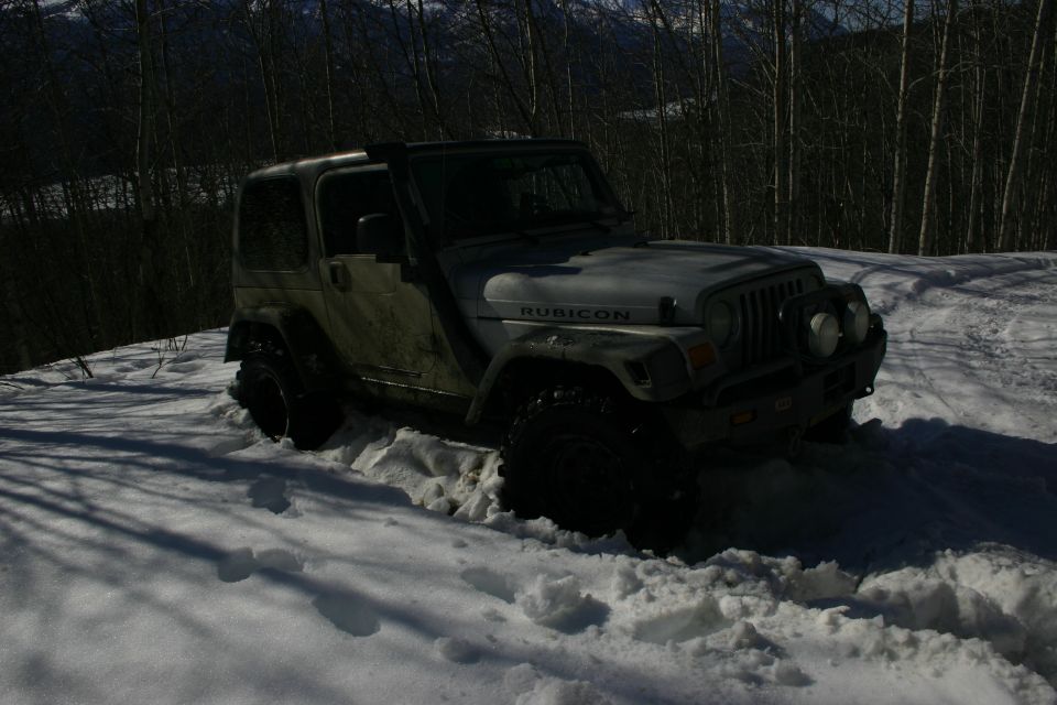 Silver Jeep TJ Rubicon stuck in snow, front 3/4 view
