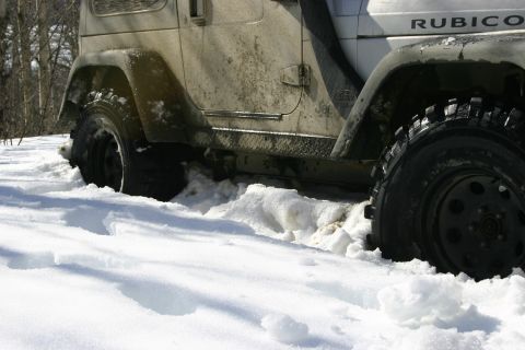 2003 Jeep TJ - Jeep TJ Rubicon stuck in snow, showing side profile and front wheel.