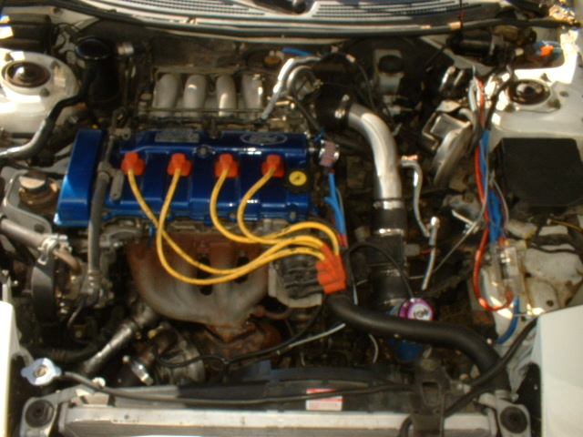 1993 Ford Probe engine bay with blue valve cover and yellow spark plug wires