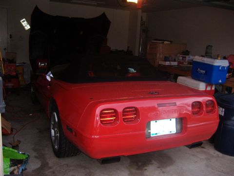 2004 Jeep Wrangler - Rear view of a red convertible sports car with its hood open in a garage.