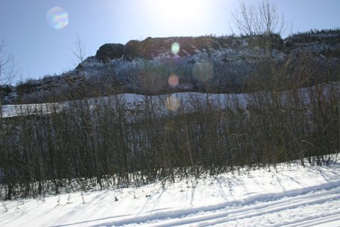 2003 Jeep TJ - A winter scene depicts a snow-covered landscape with bare trees and rocky hills under a bright, sunlit sky.