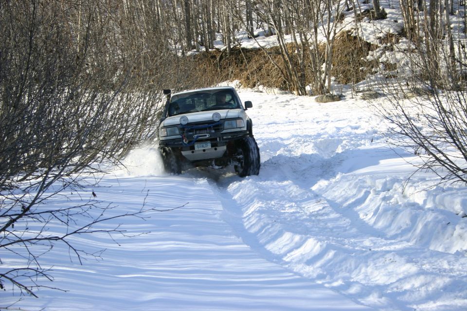 White SUV with snorkel and winch driving on a snowy path