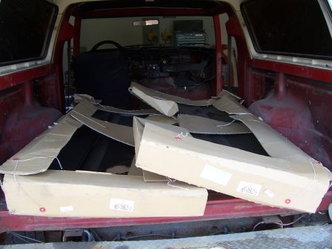 1978 Ford Bronco - Boxes of parts are loaded into the cargo area of a vehicle, obscuring the interior.