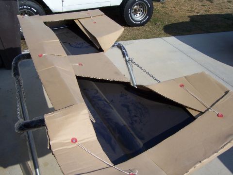 1978 Ford Bronco - A black car part is packaged in cardboard and secured with string.