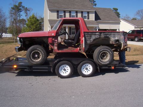 1978 Ford Bronco - A red 1978 Ford Bronco cab is transported on a trailer, showing its side profile.