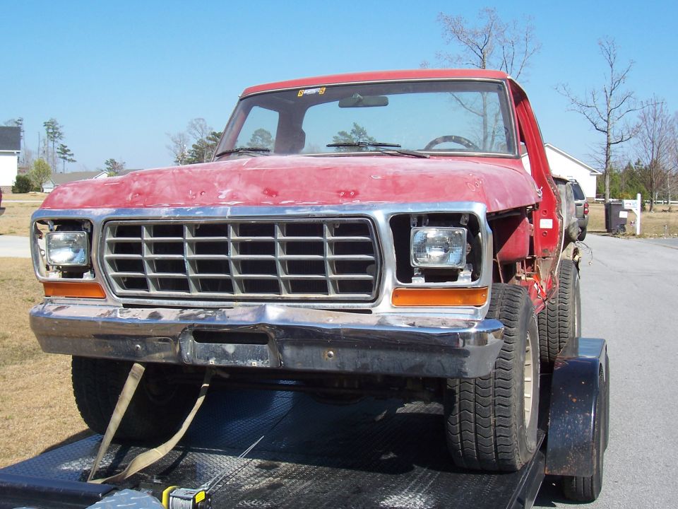 Front view of a red 1979 Ford F-150 pickup truck on a trailer