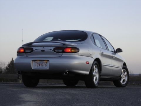1999 Ford Taurus - Rear view of a silver 1999 Ford Taurus sedan parked outdoors under a pale sky.