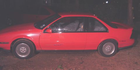 1991 Chevrolet Beretta - A red 1991 Chevrolet Beretta GT coupe is parked outdoors at night, with another red vehicle visible behind it.