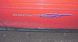 1991 Chevrolet Beretta - Close-up of the 'Beretta' nameplate on the side of a red vehicle.