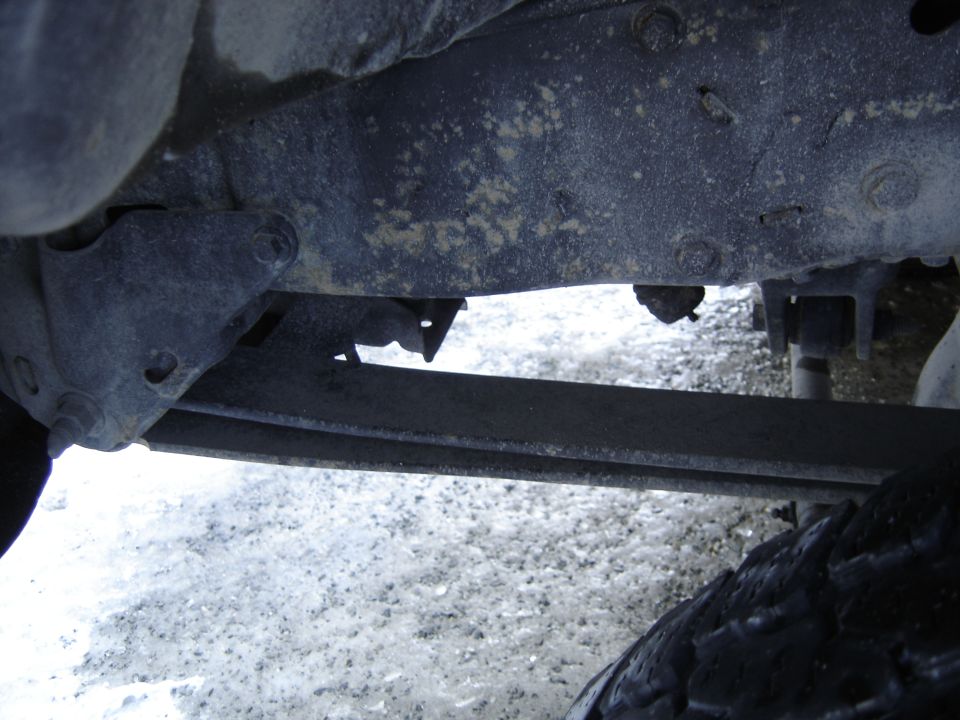 Underside view of a vehicle's frame and leaf spring. Tire visible at bottom right