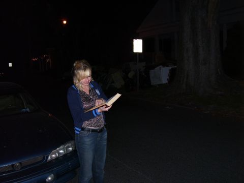 1992 Ford Bronco - A woman reads a book at night next to the front corner of a blue car.